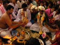 The priest praying over the coconut and other offerings. The plate is sitting on the mandala