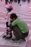 Seen in the evening. Children being taught to roller blade